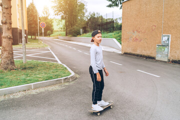Teenager skateboarder boy in baseball cap riding a skateboard on asphalt street road. Youth generation Freetime spending and active people concept image.