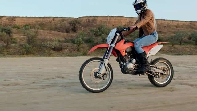 Amator rider motocross FMX rides on dirt road and trains by doing stunts on the move.