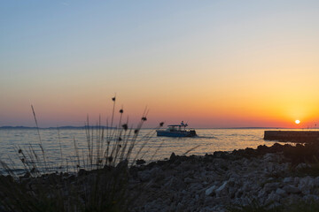 Small motor boat in the Adriatic sea near coastline at sunset on Vir island, Croatia