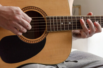 closeup on male hands playing acoustic guitar strings