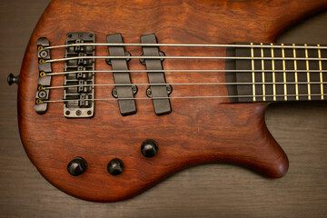 Close-up of a beautiful bass guitar made of brown wood on a wooden table. Flat lay.