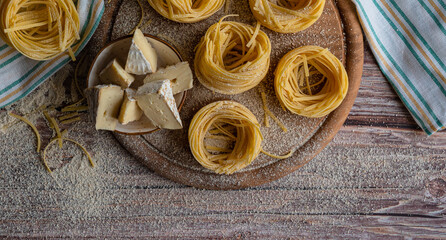 nest noodles on wooden in flour with cheese and rolling pin