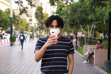 Joven latino con celular en la calle