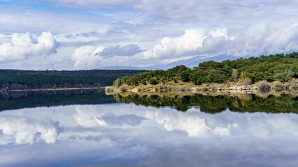 Fototapeta premium Landscape of blue lake and green plants with reflections in the water forming a symmetrical image.