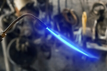 Gas burner with burning flame close up on the background of an industrial workshop