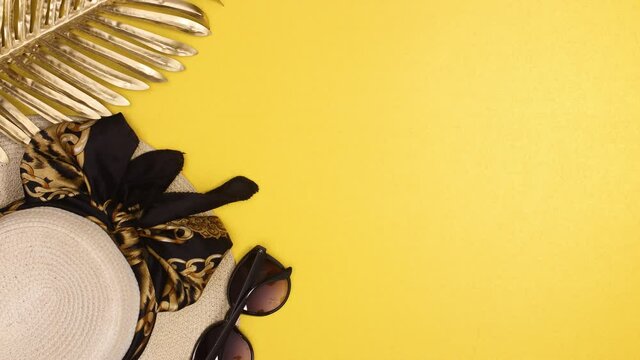 Glamour beach hat and sunglasses with gold  palm leaf appear on summer yellow background. Stop motion