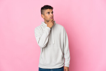 Young Brazilian man isolated on pink background and looking up