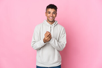 Young Brazilian man isolated on pink background laughing