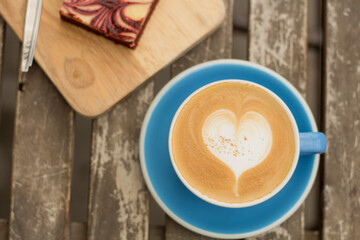 Caffe latte art on wooden table with brownie 