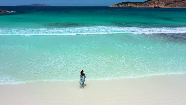 "Girl in a summer dress is running into Hellfire bay near Esperance viewed during a cloudy day, Australia"