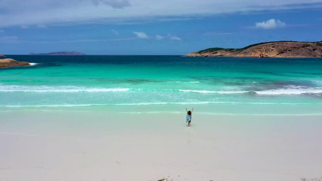 "Girl in a summer dress is running into Hellfire bay near Esperance viewed during a cloudy day, Australia"