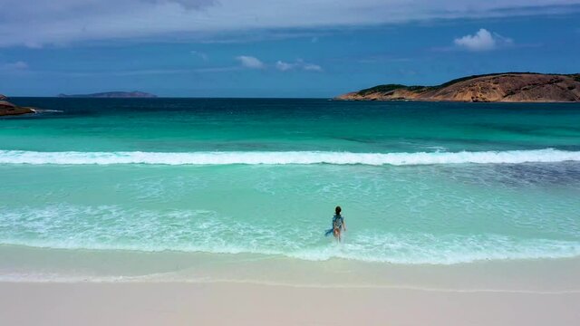 "Girl in a summer dress is running into Hellfire bay near Esperance viewed during a cloudy day, Australia"