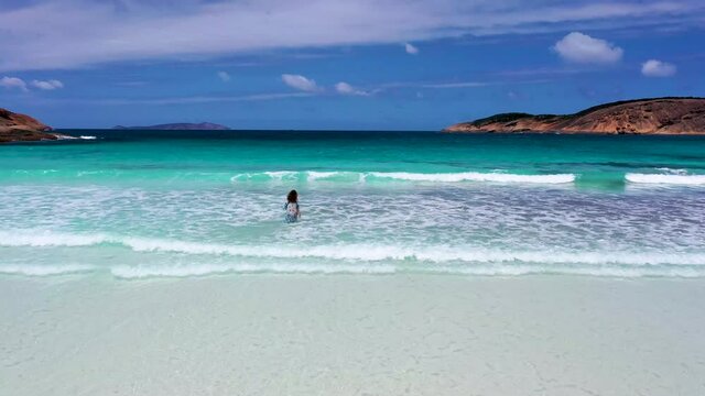 "Girl in a summer dress is running into Hellfire bay near Esperance viewed during a cloudy day, Australia"