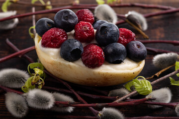 White chocolate egg filled with passion fruit mousse decorated with dried cranberries and fresh blueberries
