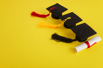 Three Academic hats with diploma on yellow background. Graduation theme