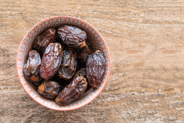Medjool date fruits in ceramic bowl on wooden background . Dried fruits. Food background.