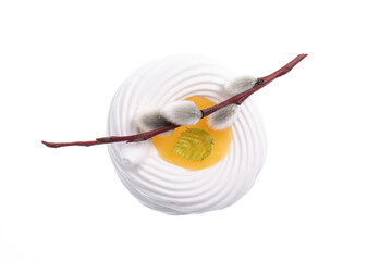 White meringue cookie with yellow lemon cream in the middle decorated with a stick from a willow tree isolated on white. Easter theme