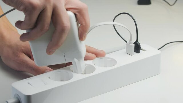 Close-up of a male hand plugging cables into a power outlet. Modern convenient multi-port usb charger for devices.