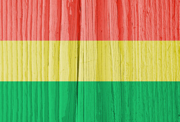 The flag of Bolivia on dry wooden surface, cracked with age. Light pale faded paint. Background, wallpaper or backdrop with Bolivian national symbol. Old wood. Hard sunlight with shadows