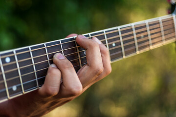 left hand of a man who plays the guitar