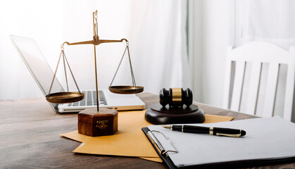 Justice and law concept.Male judge in a courtroom with the gavel, working with, computer and docking keyboard, eyeglasses, on table in morning light