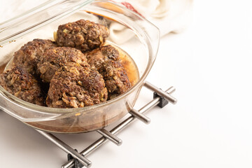 Cooking homemade meat cutlets. Roasted meatballs in a glass bowl with a lid. White background
