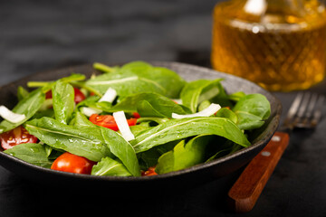 Arugula salad with tomatoes on dark background.