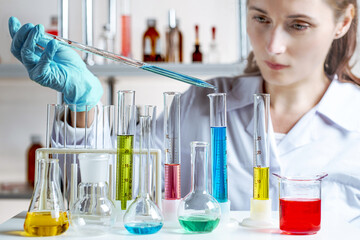 Cropped view of woman laboratory assistant pipetting into graduated flask. Focus on the drop.