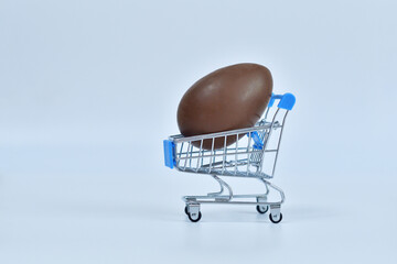 Shopping trolley with chokolate easter eggs on white background. Easter sale.