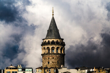 Fototapeta premium Close up of Galata Tower's observation terrace with tourists and dome, with large cloudy sky brewing a storm in the background with large copy space.