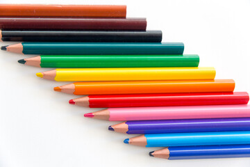 Top view of a series of colorful thick wooden crayons with tips and rears, diagonally arranged in the frame.
