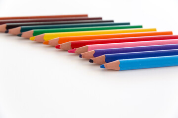 Selective focus close up of a number of colorful, thick crayons with tips in the foreground, isolated on white neutral background.