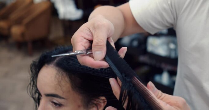 A young brunette woman in a beauty salon has a haircut in a barbershop, in a barbershop a man does a hairstyle for a brunette in a barbershop, a man hairdresser combs his hair. 4K slow motion.