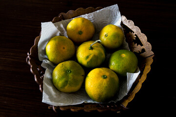 Top view close up of a basket full fresh kinnow mandarins with their peels on. © MeteBasar