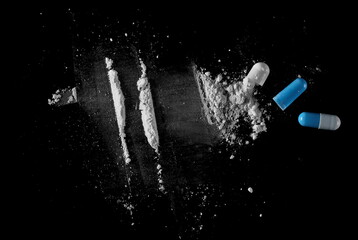 Blue white pills, open capsules with powder and cocaine lines isolated on black background, top view