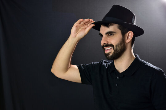 Happy young man wearing hat on black background.
