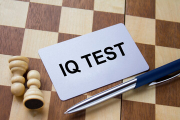 Business card with text IQ Test on a chess board with pen and eyeglasses