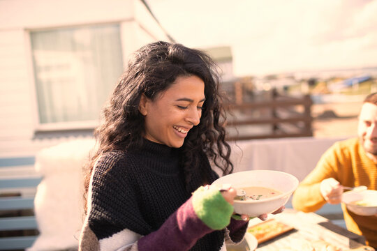 Happy woman enjoying chowder on sunny patio