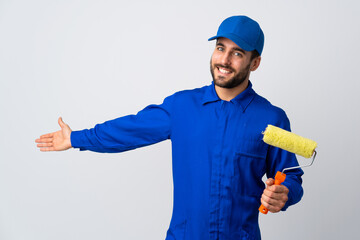 Painter man holding a paint roller isolated on white background extending hands to the side for...