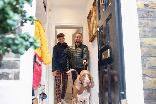Happy gay male couple leaving house to walk dog
