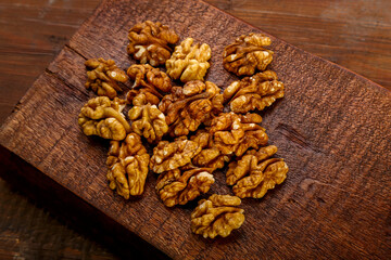 Walnuts sprinkled on a square board on a wooden table.