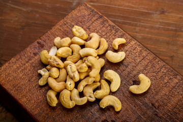 Cashew nuts scattered on a square board on a wooden table.