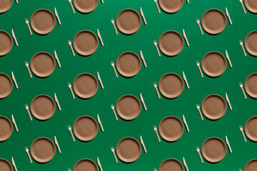 seamless pattern of paper plates, wooden forks and knifes on a green background. zero waste, recycling, reusable concept