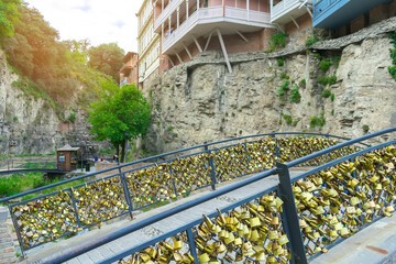 Bridge with golden locks and traditional buildings with carved wooden colorful balconies on rock, cliff in Tbilisi, Georgia - Tbilisi, Georgia - June 11, 2019