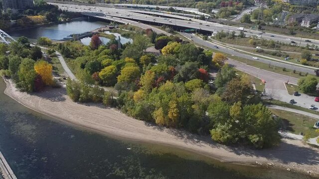 Aerial flight backwards while panning up to reveal Gardiner Expressway Humber Bay Bridge and passenger train passing in the distance