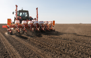Fototapeta premium Farmer with tractor seeding crops at field