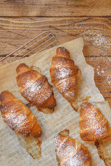 French fresh crusty croissants on a wooden table top view