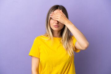 Young woman over isolated purple background covering eyes by hands. Do not want to see something