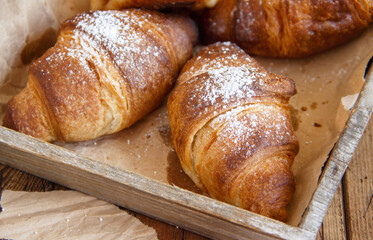 French fresh crusty croissants on a wooden tray close up