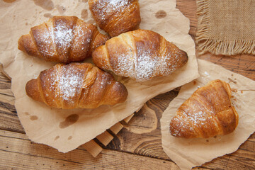 French fresh crusty croissants on a wooden table top view